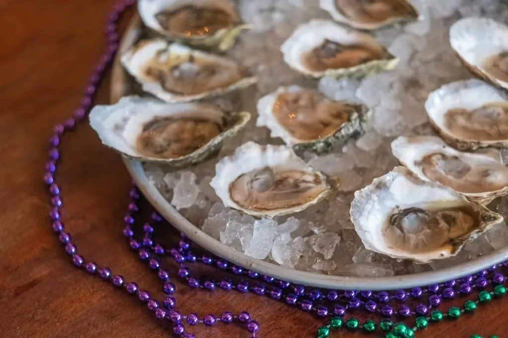 Platter of shucked oysters on ice with Mardi Gras beads.