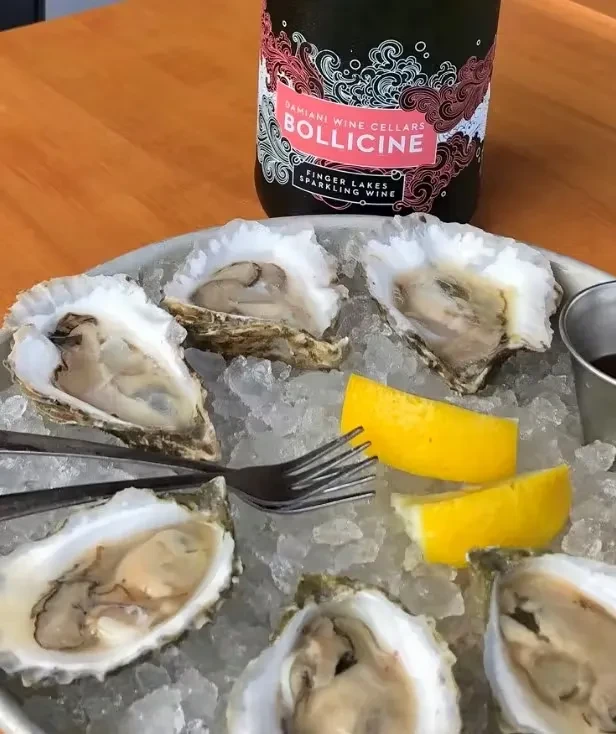 Six shucked oysters on ice with lemon and sparkling wine.