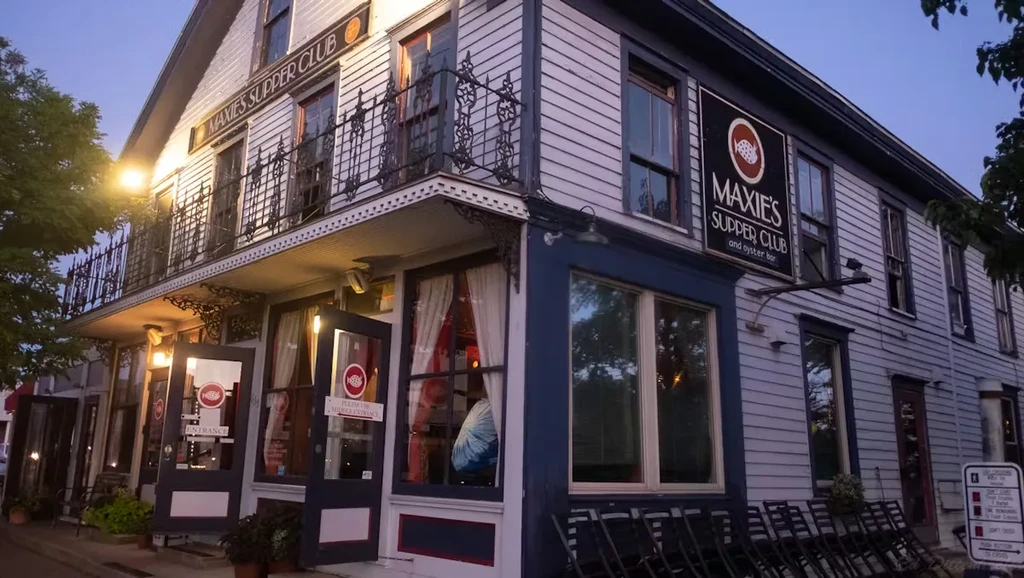 Two-story Maxie's Supper Club exterior with wrought-iron balcony at dusk.