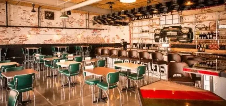 Industrial-chic restaurant interior with exposed brick, bar, and car decor.