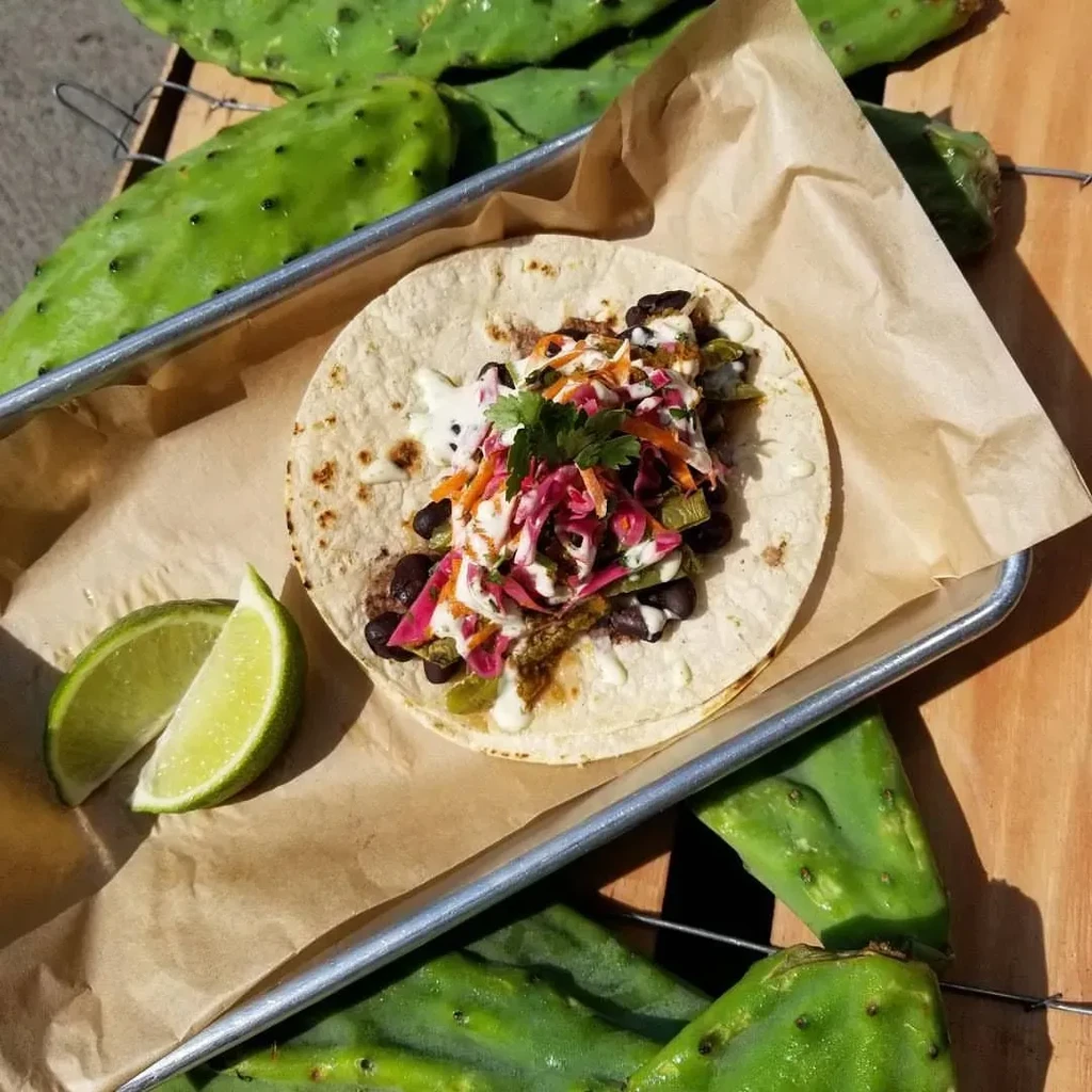 Taco with beans, slaw, crema, and lime, served with nopales.