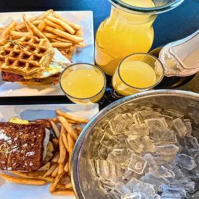 Overhead brunch spread with waffle, French toast, fries, and mimosas.