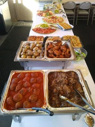 A well-stocked buffet table with hot dishes, appetizers, fruits, and desserts.