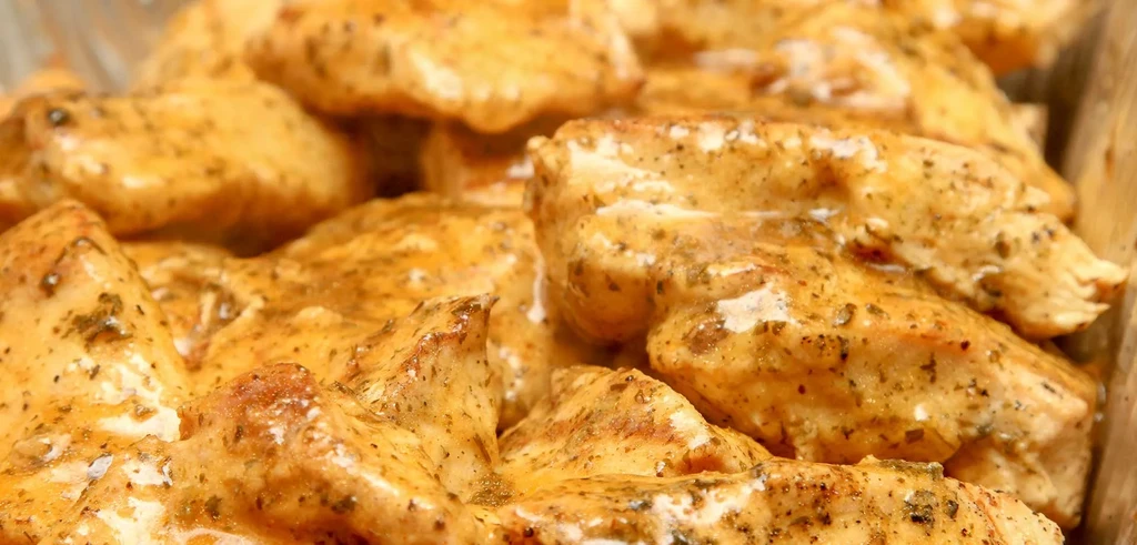 Chicken pieces coated in creamy orange sauce with herbs and spices.