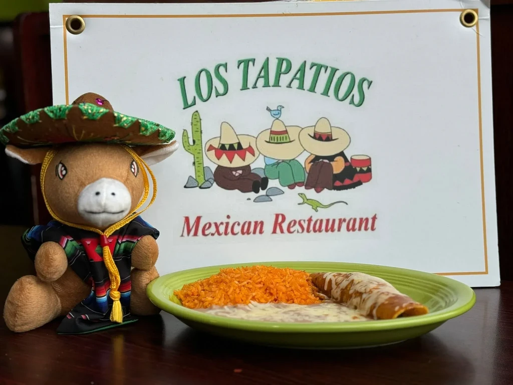 Plate of Mexican food, plush donkey, Los Tapatios restaurant sign.