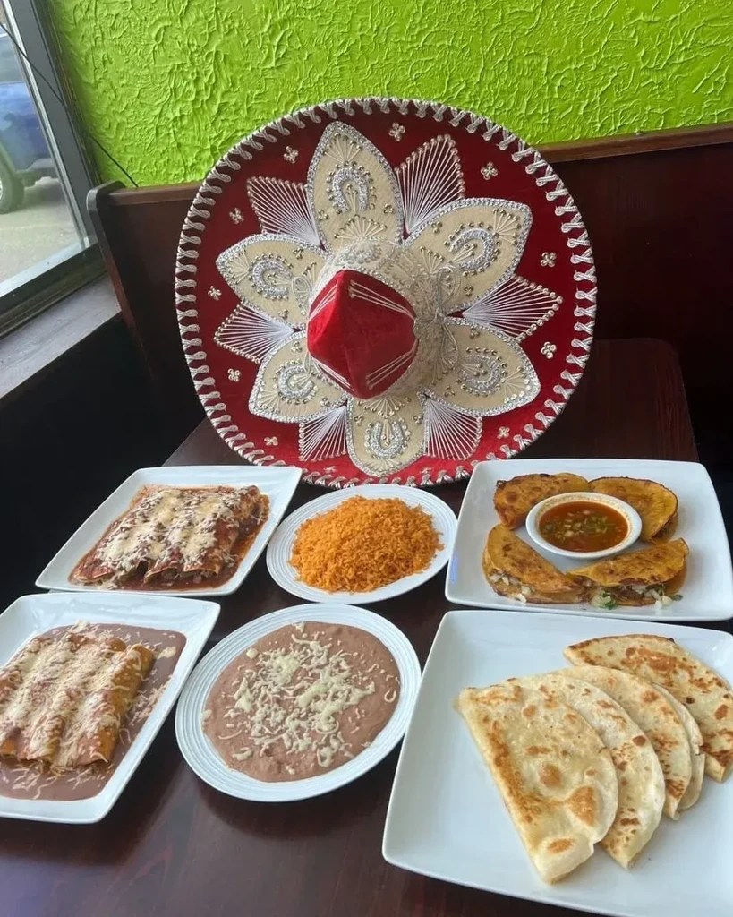 Ornate sombrero above a spread of assorted Mexican dishes.