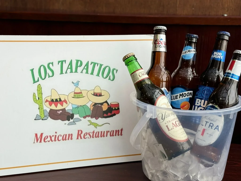 Ice bucket of assorted beers next to a Mexican restaurant sign.