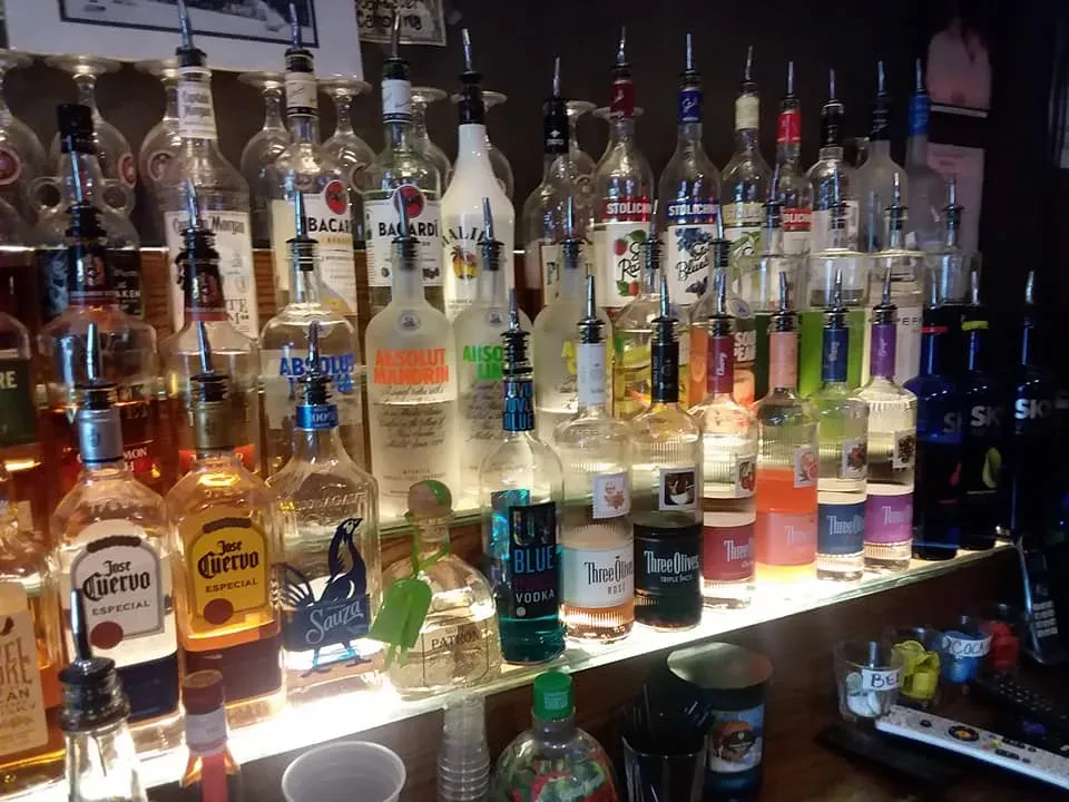 Well-stocked bar display with illuminated bottles of various spirits.