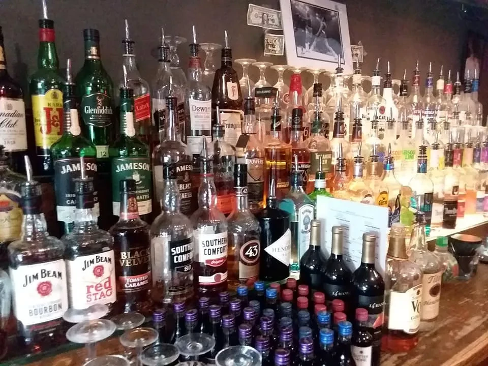 Well-stocked bar counter featuring various liquor bottles, glasses, and a menu.