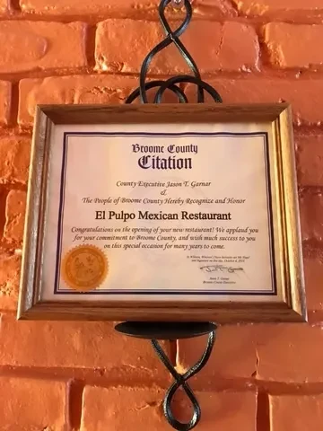 Framed Broome County Citation for El Pulpo Mexican Restaurant on brick wall.