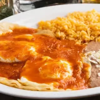 Huevos Rancheros with fried eggs, orange salsa, rice, beans, and cheese.
