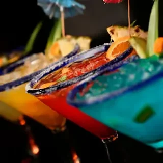 Four brightly colored, garnished margaritas in a row.