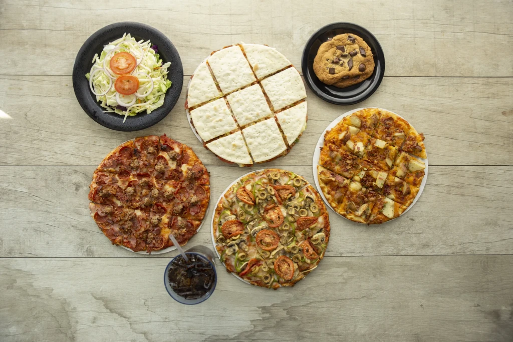 Overhead: salad, flatbread, cookie, three pizzas, and a beverage.