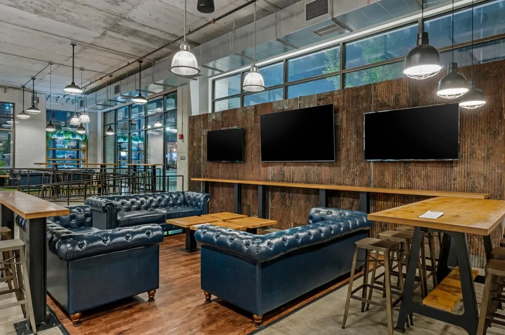 Industrial-chic restaurant interior with concrete, metal walls, and tufted sofas.