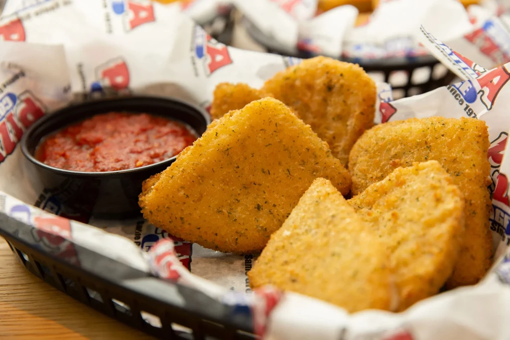 Golden-brown breaded fried food and marinara sauce in a basket.