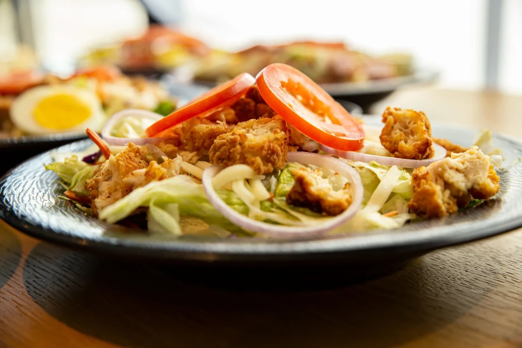 Close-up of a fresh salad with fried chicken, lettuce, tomato, onion.