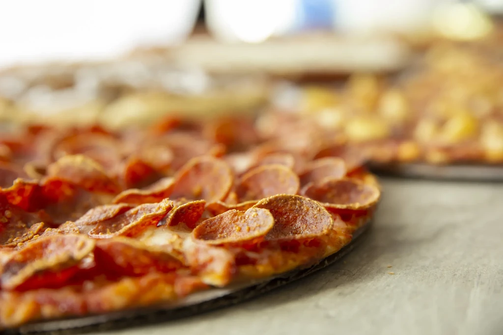 Close-up, low-angle pepperoni pizza with crisped, curled slices and melted cheese.