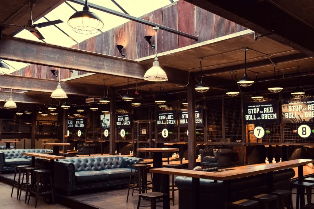 Industrial-chic venue interior with mini-bowling lanes and lounge seating.