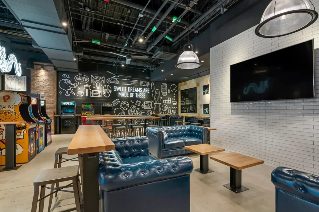 Playful, industrial restaurant interior with lounge seating and arcade games.