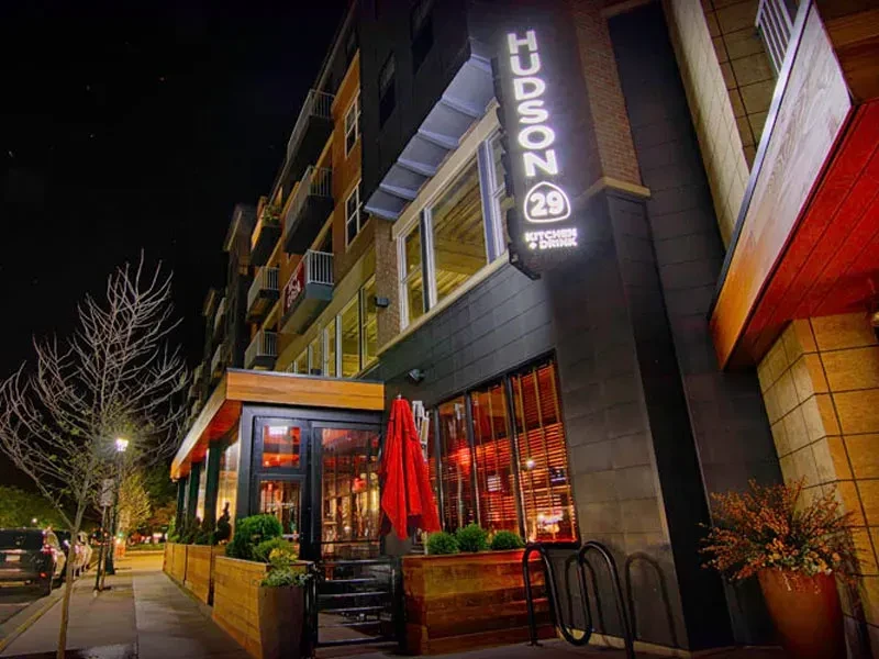 HUDSON 29 KITCHEN + DRINK exterior at night, illuminated sign, patio.