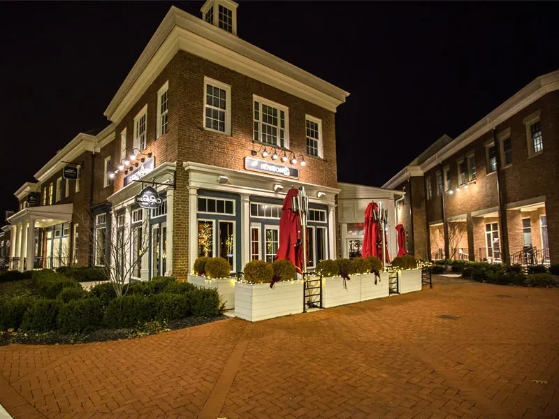 Lit brick building for 'Hubbard's' with folded patio umbrellas at night.