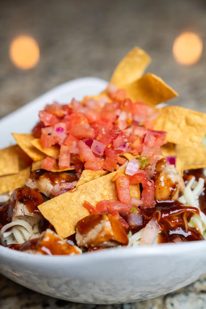 Top-down chicken bowl with pico de gallo, chips, and dark sauce.