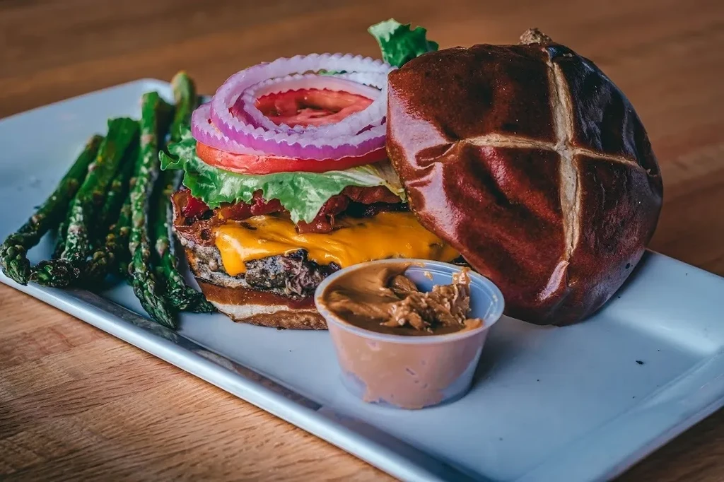 Gourmet pretzel bun burger with asparagus and peanut butter.