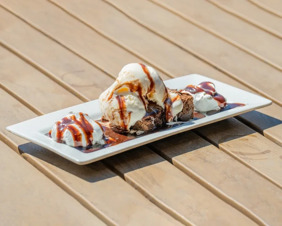 Brownie topped with vanilla ice cream, chocolate sauce, and whipped cream.