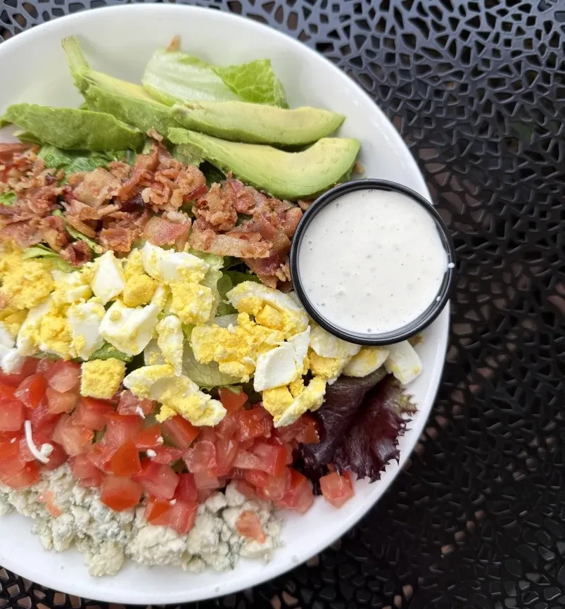 Cobb salad with avocado, bacon, egg, tomato, blue cheese, and dressing.
