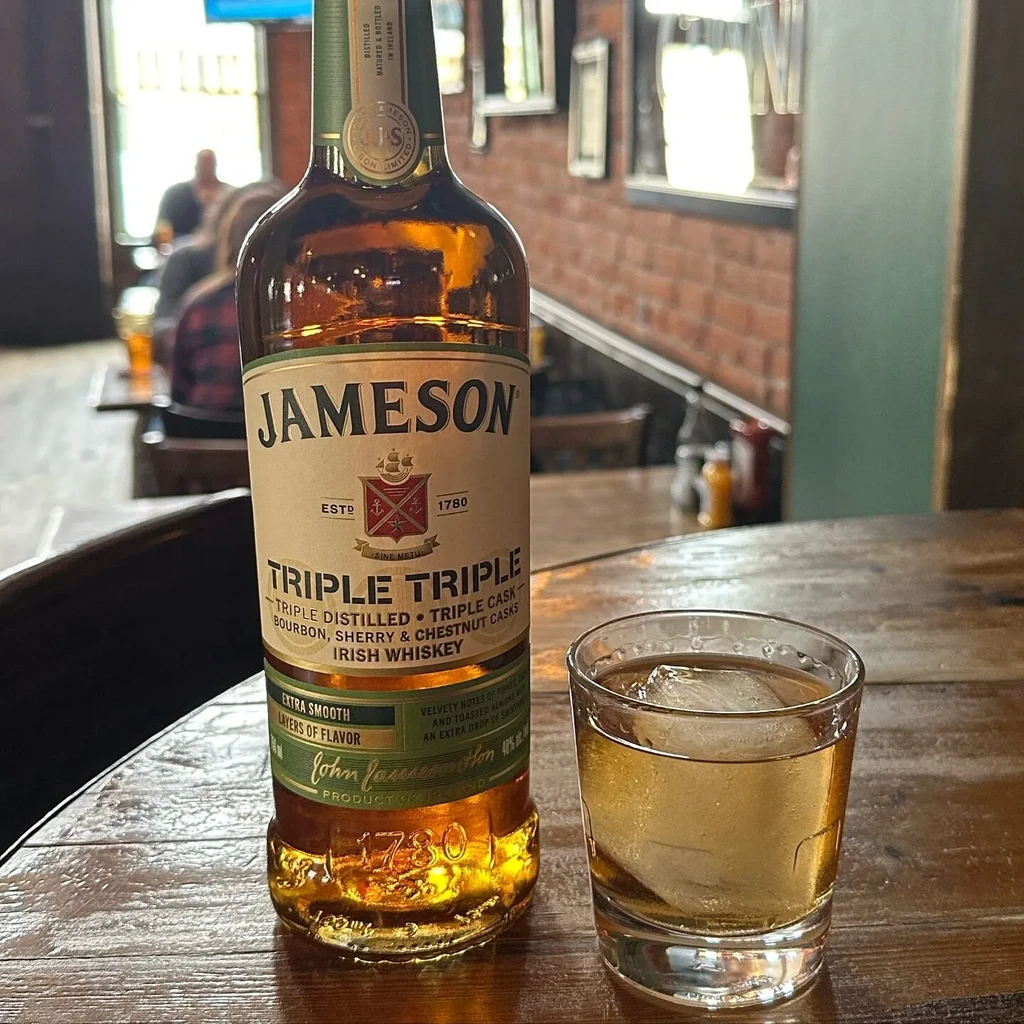 Jameson 'Triple Triple' bottle, glass with ice, on a bar.