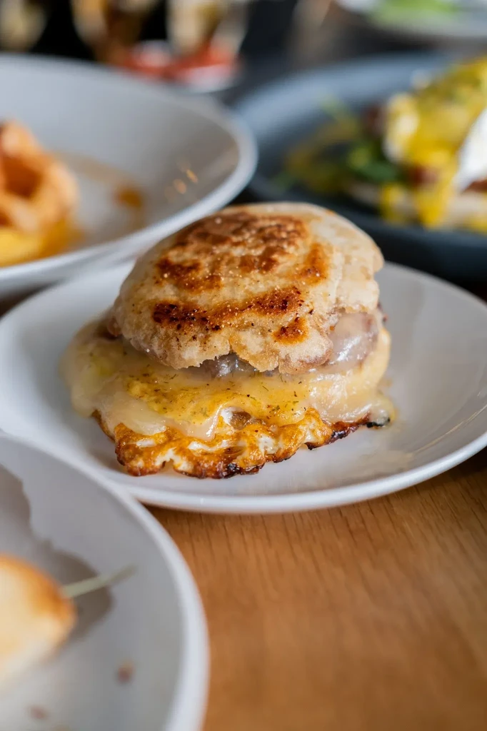 Toasted English muffin breakfast sandwich with melted cheese and fried egg.
