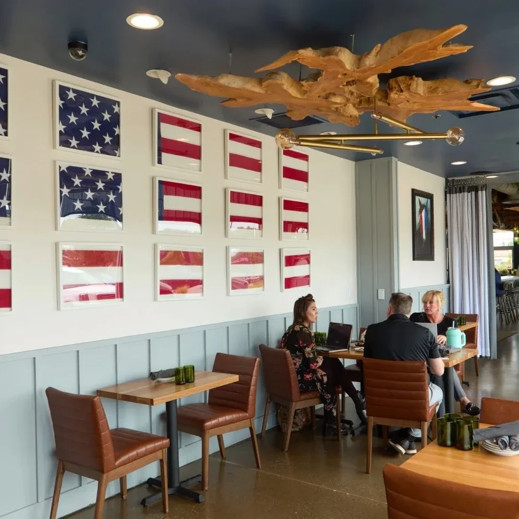 Restaurant interior: American flag wall decor, sculptural chandelier, people dining.