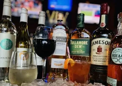 Close-up of bottles and glasses of wine, whiskey, and cocktails on ice.