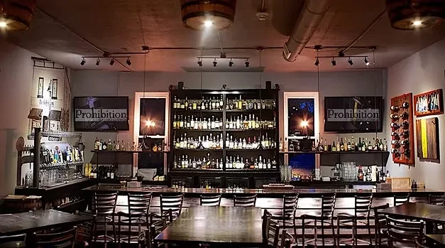 Industrial-chic bar with full liquor backbar, beer taps, and dark seating.