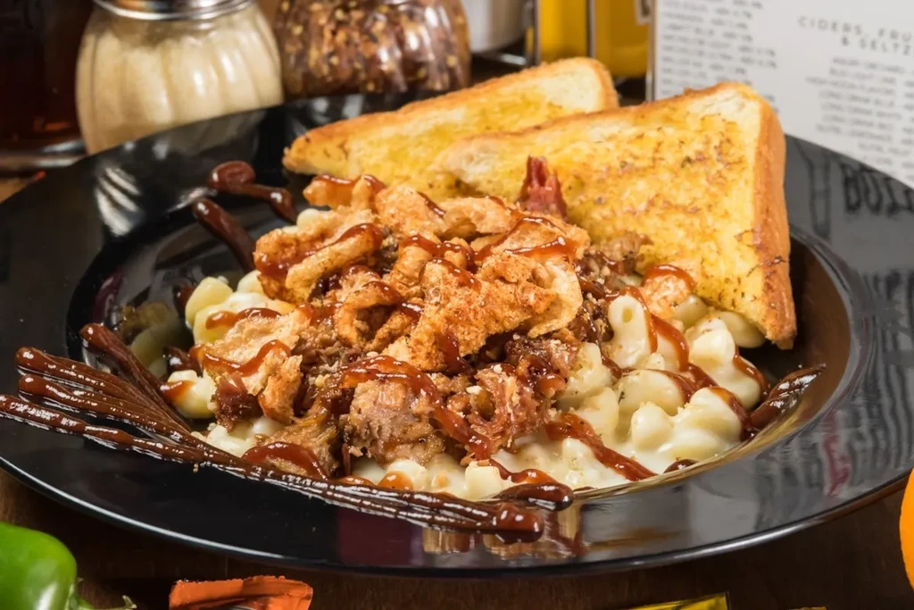 Macaroni and cheese with pulled pork, chicharrons, BBQ sauce, and toast.