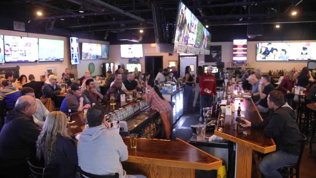 Bustling sports bar with many patrons watching sports on TVs.