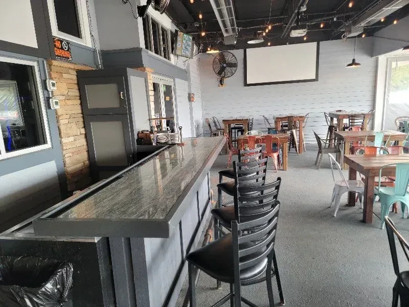 Empty industrial-chic restaurant interior with a bar and varied seating.