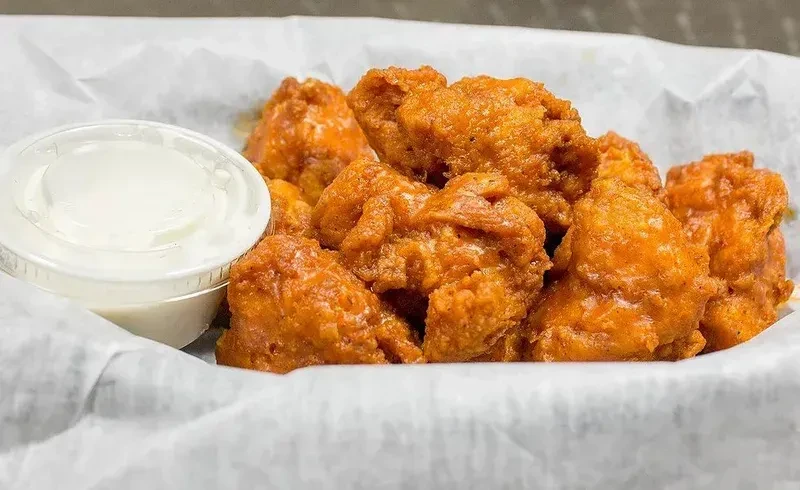 Crispy golden-brown fried chicken and dipping sauce in separate containers.