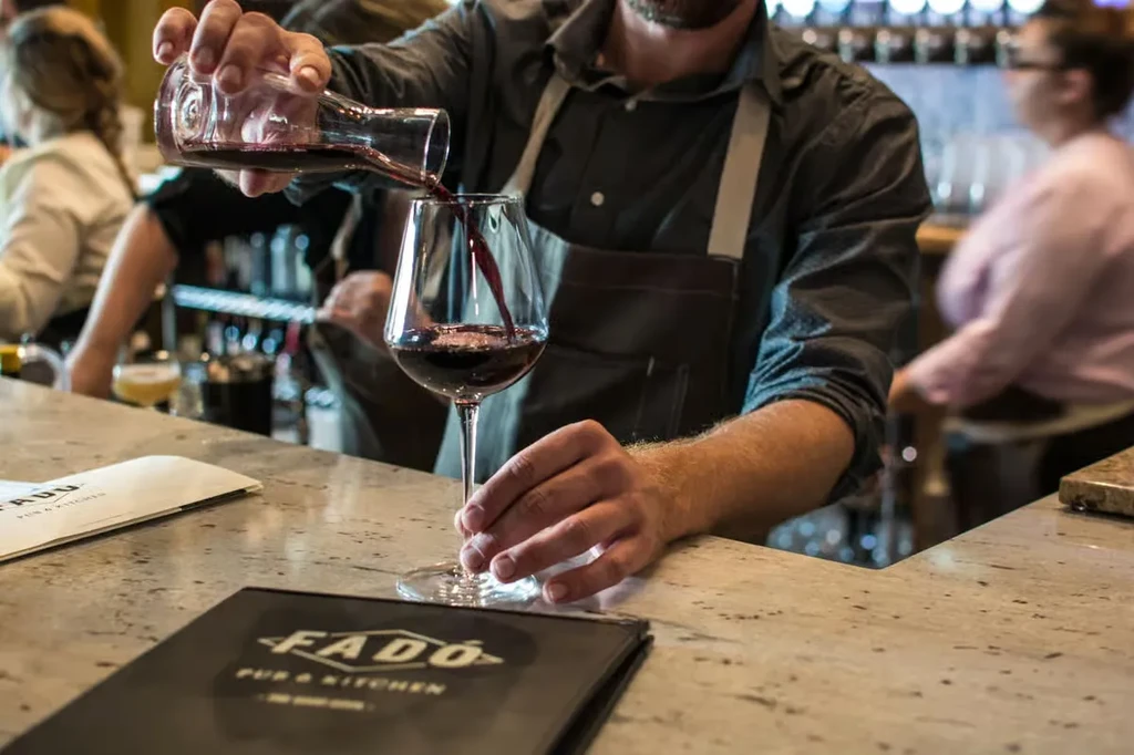 Bartender pouring red wine into a glass at FADO PUB & KITCHEN.