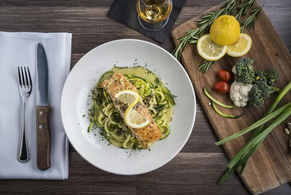 Top-down view of plated salmon, zucchini noodles, and fresh ingredients.