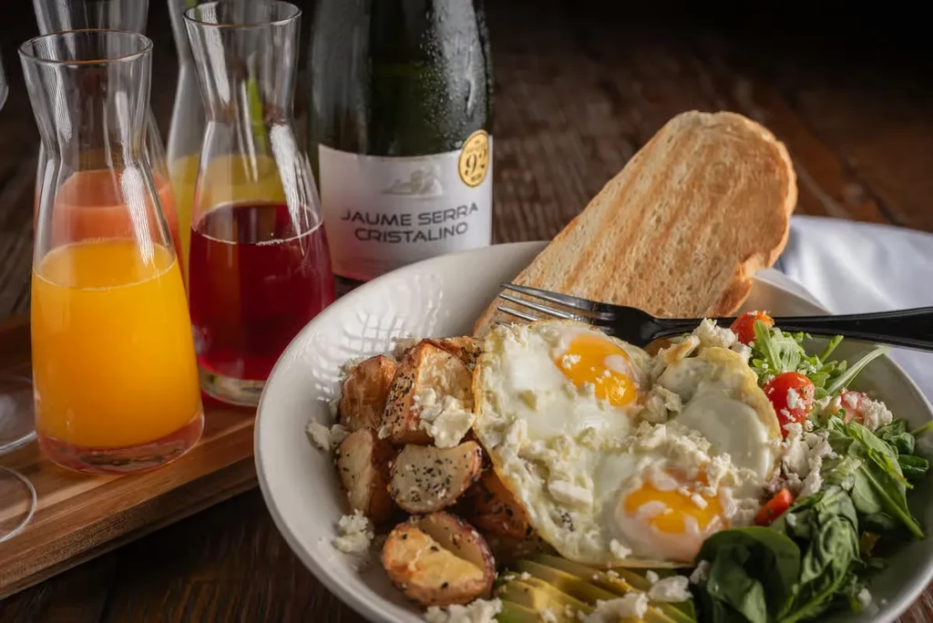Brunch spread: eggs, potatoes, salad, juices, and sparkling wine.