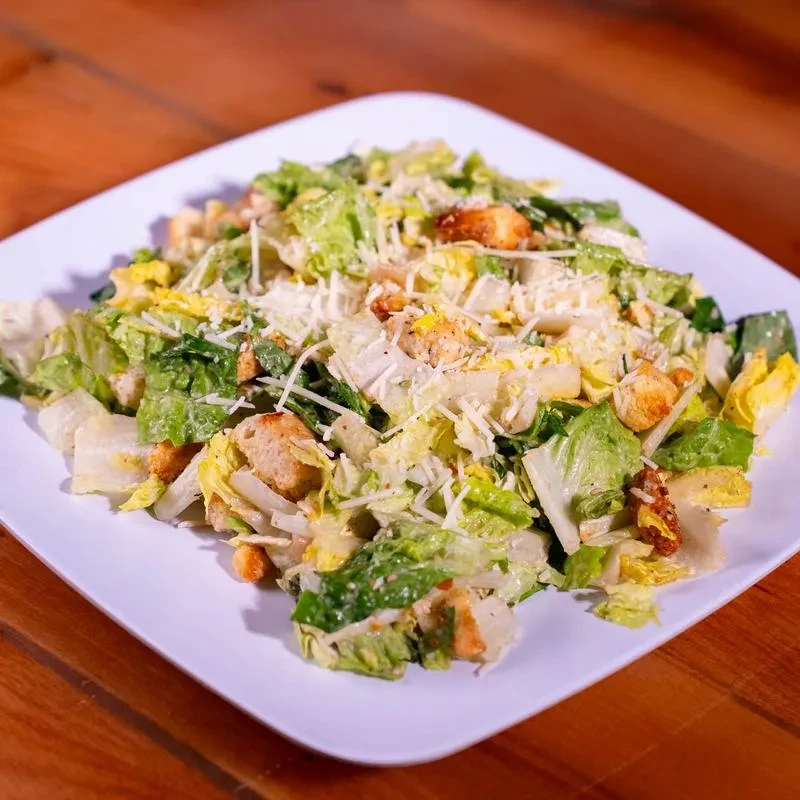 Close-up Caesar salad with romaine, chicken, Parmesan, and croutons.