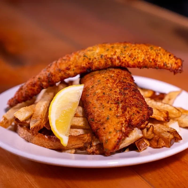 Classic fish and chips with lemon on a white plate.