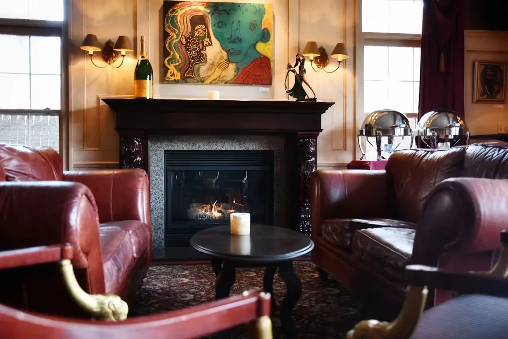 Lounge with fireplace, abstract art, champagne, and red leather chairs.