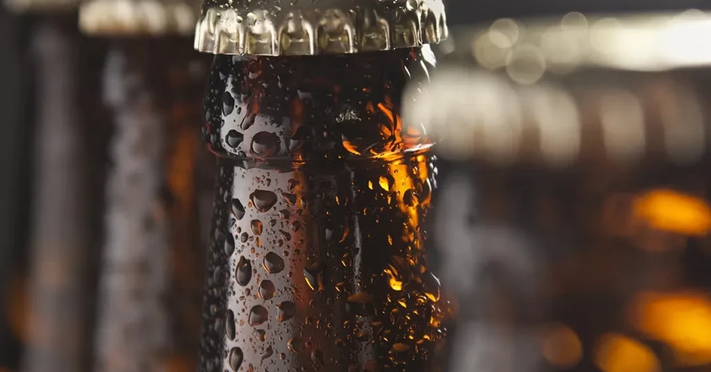 A cold, dark brown bottle with condensation and a metallic cap.