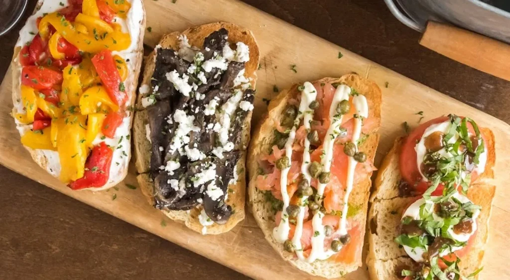 Rustic wooden board with four distinct bruschetta types.