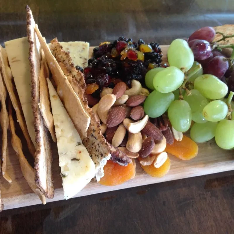 Charcuterie board with cheese, crackers, nuts, dried fruit, and fresh grapes.