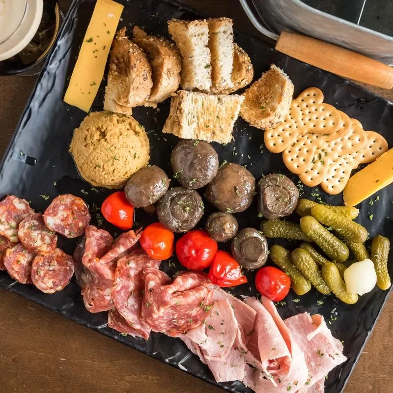 High-angle view: A black charcuterie board with meats, cheeses, and vegetables.
