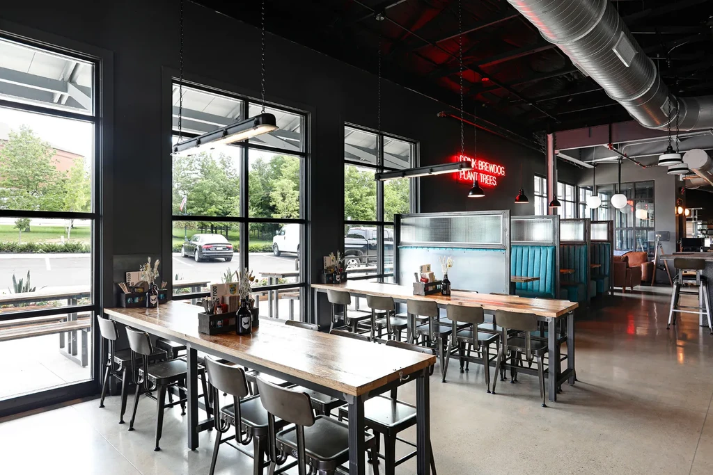 Industrial-chic restaurant interior with wooden tables, blue booths, and "DRINK BREWDOG" sign.