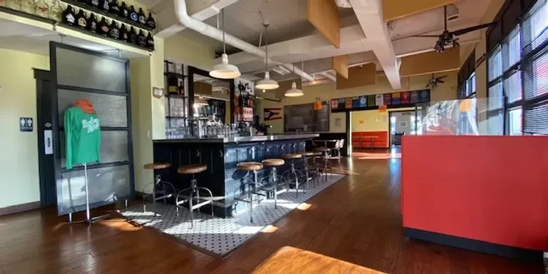 Industrial bar interior with long counter, beer taps, and checkered floor.